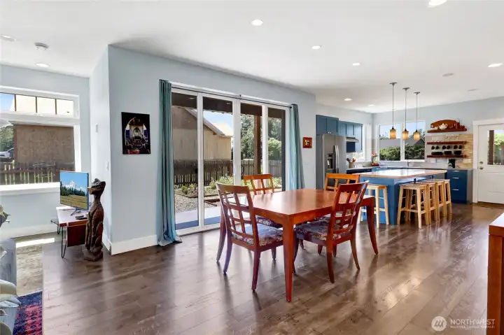 The heart of the home features an open-concept kitchen, dining, and living room with durable LVP flooring throughout. A sliding door leads to one of two covered patios, creating seamless indoor-outdoor living and easy access to the raised garden beds.