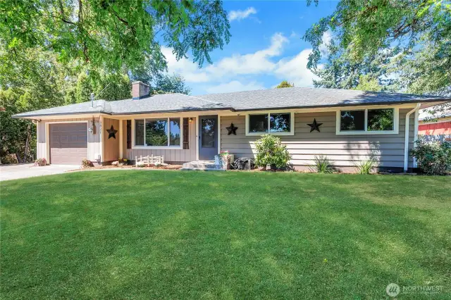 Framed by shade trees and lush green lawn, this angle showcases the home’s symmetrical charm, architectural simplicity, and a welcoming entry. It’s the kind of place that feels like home the moment you arrive.