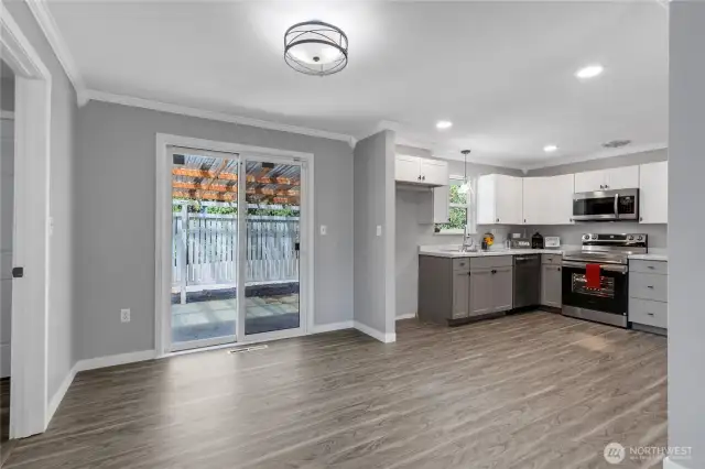 Enjoy effortless indoor-outdoor living with this open dining area just off the kitchen, featuring a stylish modern light fixture and sliding glass doors that lead to the covered patio—ideal for entertaining or summer BBQs.