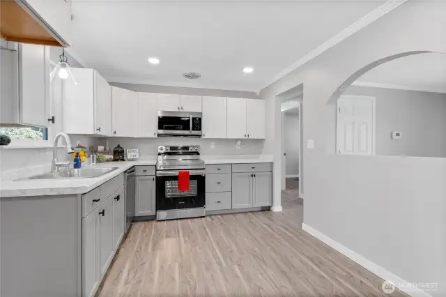 This freshly updated kitchen shines with sleek stainless steel appliances, quartz-style countertops, and shaker cabinets. The arched opening provides a visual connection to the living area while keeping kitchen activity tucked away.