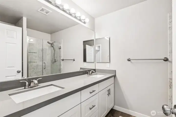 The light and bright primary en-suite bathroom with a dual sink quartz vanity.