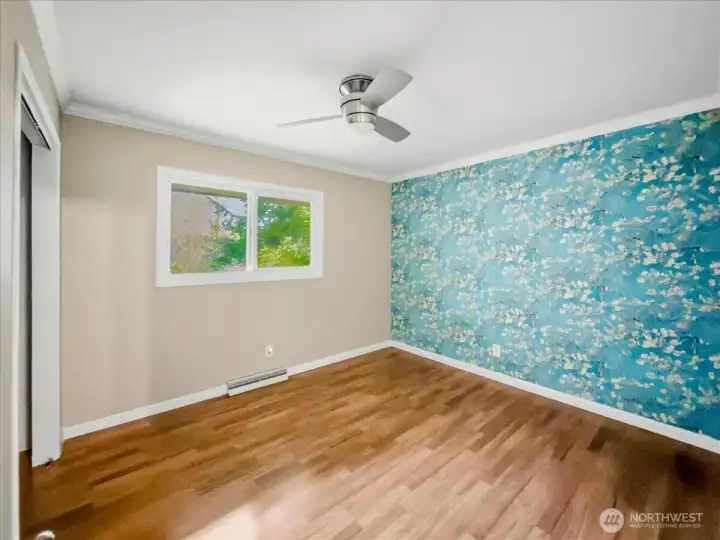 Private wing, main floor bedroom with ceiling fan and grass cloth access wall. Bedroom 1 of 4.