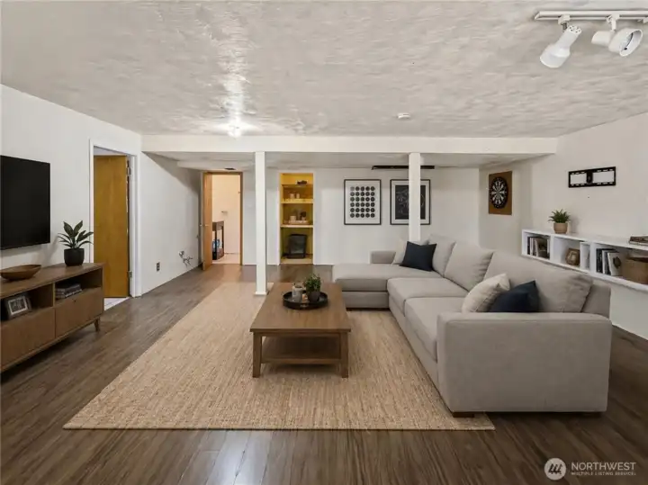 Lower level with a separate entrance and free-standing gas fireplace, offering strong potential for a private living area. To the left, you’ll find a spacious laundry room with a utility sink and direct access to the attached garage. Along the back are a convenient powder room and a large storage area [virtually staged]