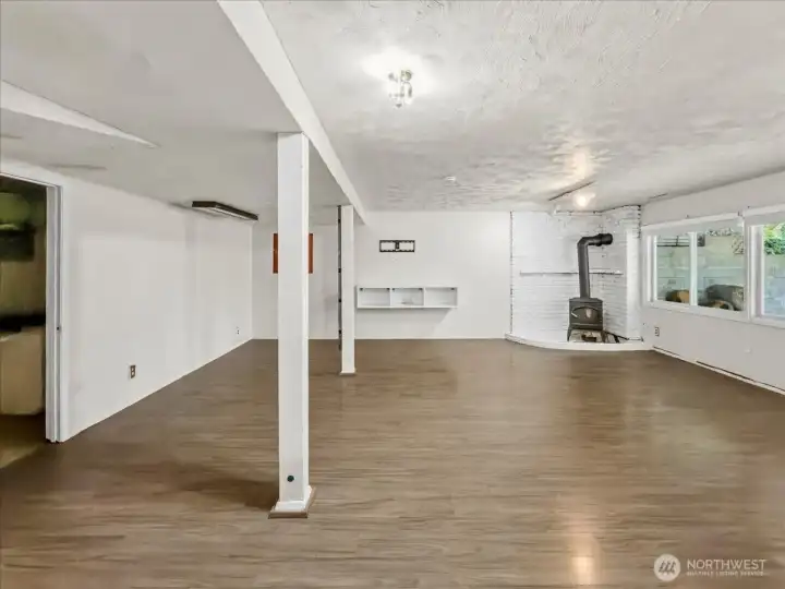 Lower level with a separate entrance and free-standing gas fireplace, offering strong potential for a private living area. To the left, you’ll find a spacious laundry room with a utility sink and direct access to the attached garage. Along the back are a convenient powder room and a large storage area.