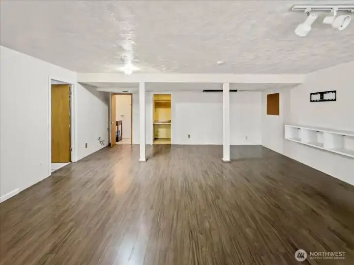 Lower level with a separate entrance and free-standing gas fireplace, offering strong potential for a private living area. To the left, you’ll find a spacious laundry room with a utility sink and direct access to the attached garage. Along the back are a convenient powder room and a large storage area.