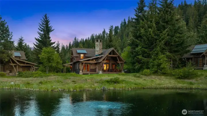 Can you hear the evening creatures? The cabin lights glow softly as dusk settles over the water and towering pines.