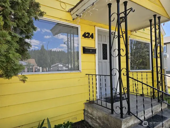 Darling, covered front porch with black iron railings and white PVC fencing along the front