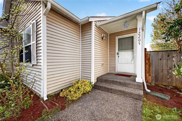 A charming cement walkway welcomes you to a covered front entry—perfect for greeting guests year-round