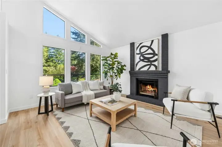 Striking architectural features with the vaulted ceilings, dark accented fireplace, and wall of windows.