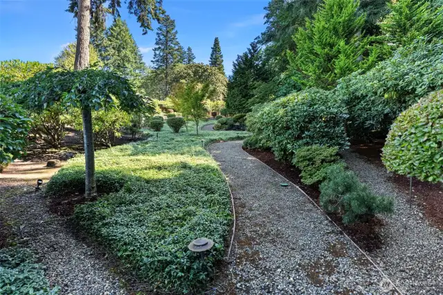 Lush landscaping behind home with manicured walking trails
