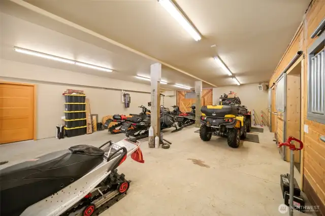 Reverse angle from front entry gives perspective of stall depth/length.  Free standing faucet for stall cleanout and drains thoughout garage area and stalls.  Man door is to living space bath and hallway to bunk area.