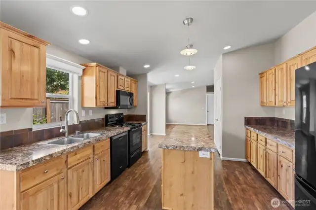 Spacious, open-concept kitchen featuring natural wood cabinetry, durable countertops, and a large center island—perfect for cooking and entertaining. This energy-efficient home in Lacey’s 55+ Lakeview Meadows community offers both beauty and functionality.