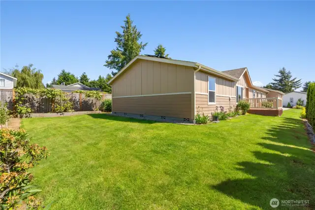 Spacious backyard in Lacey, WA—perfect for gardening, relaxing, or entertaining. This beautifully maintained outdoor space offers privacy, lush green lawn, and vibrant landscaping—ideal for active 55+ living in the Lakeview Meadows community.