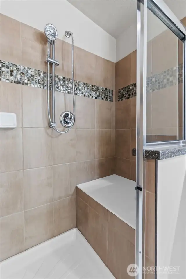 Upgraded walk-in shower with built-in bench seating, custom tile surround, and handheld shower head—designed for comfort, safety, and accessibility. A standout feature in the luxurious primary suite of this 55+ Energy Star Certified home in Lacey’s Lakeview Meadows community.