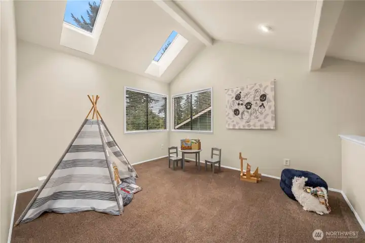 The loft continues the high vaulted ceilings with a flood of light from the upper windows.