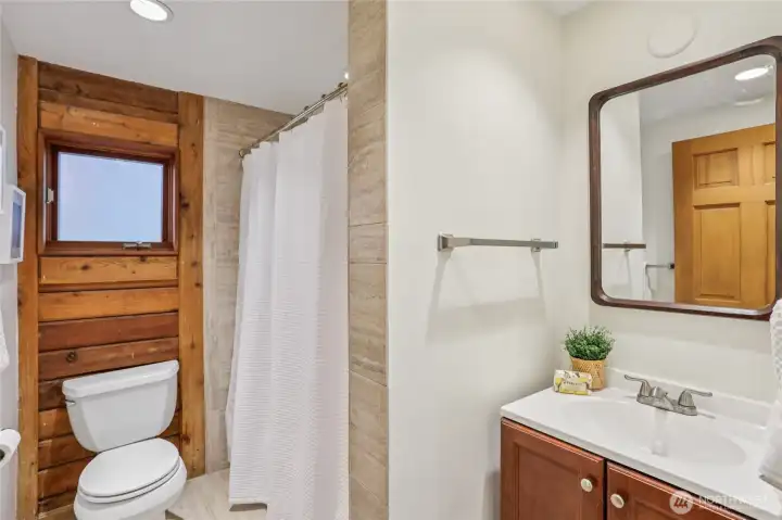 Main level bath with modern tile, full shower, and relaxing tub.
