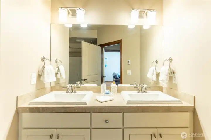 Primary bathroom has white cabinetry and double sinks.