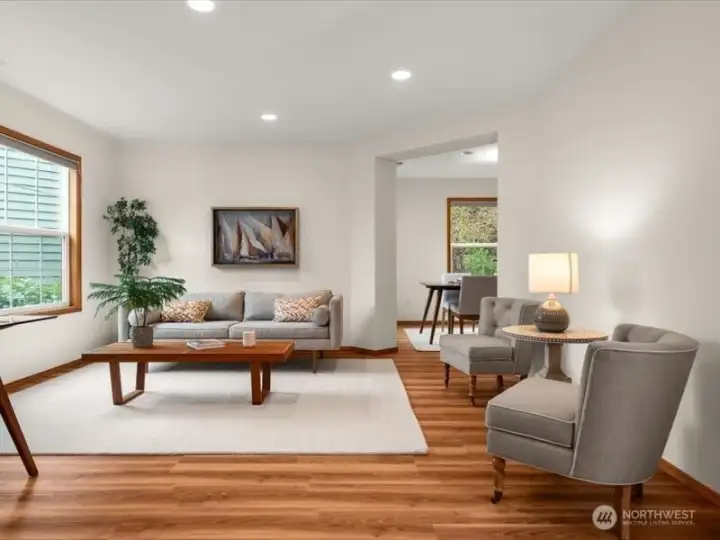 Sunlit living room with large front windows illuminating light throughout