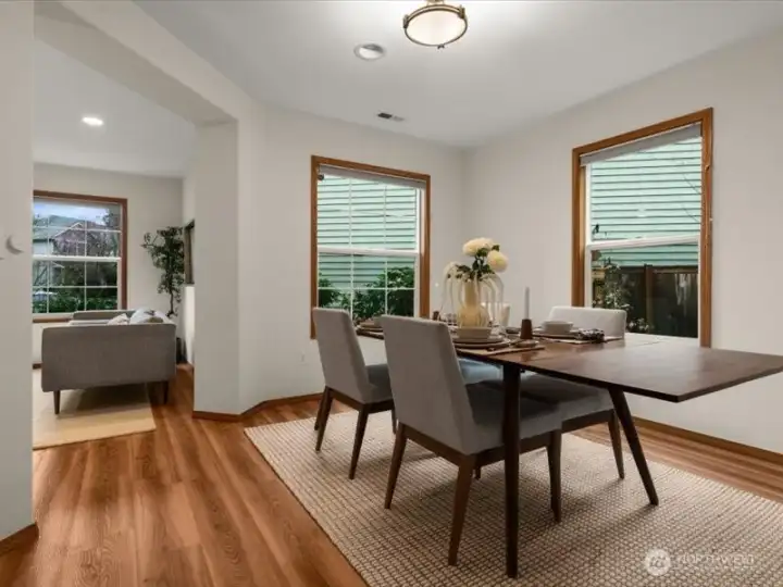 A dining room with ambiance, offering corner windows with front and side yard views, and rich, warm, wood-like flooring