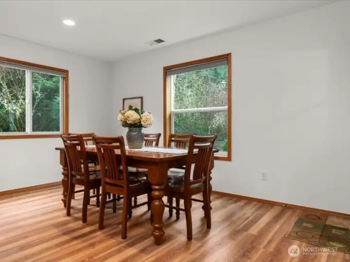 Nature wrapped, kitchen eating nook with windows on two sides, creating light and scenic backyard views