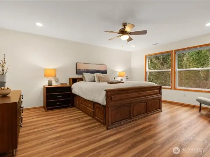 Sizable primary suite, with adjoining office, offers a ceiling fan and oversized windows to maximize the picturesque backyard views