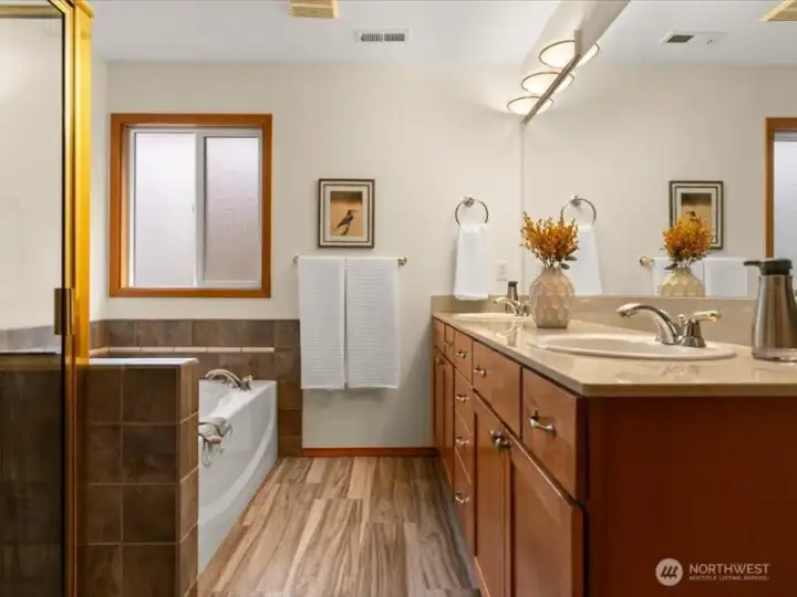 Elegant primary bathroom with walk-in tiled shower, double sinks, soaking tub and walk-in closet