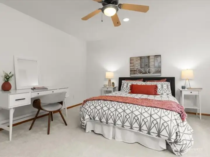 Generous secondary bedroom with walk-in closet and ceiling fan, appointed with plush new carpeting, accommodates a queen-sized bed and dresser