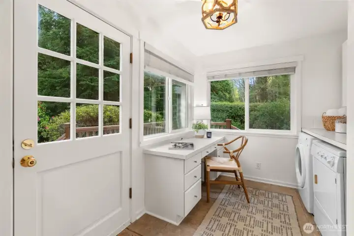 The door open to the wraparound deck, lawn and gardens. This is the mudroom/laundry room.