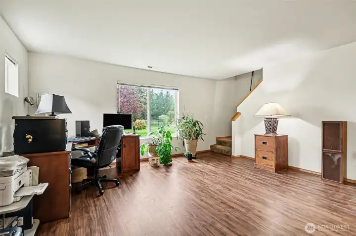 Staircase from lower level ante room leading up to the primary suite. Large window frames the backyard, overlooking golf course.