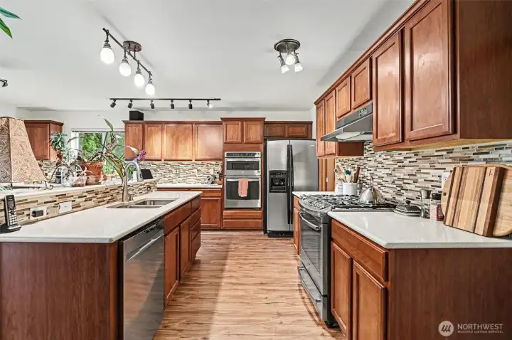 Gorgeous kitchen with solid surface countertops, tile backsplash and newer stainless steel appliances, including two ovens!