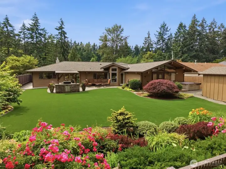 Gorgeous back yard bordered by colorful gardens.