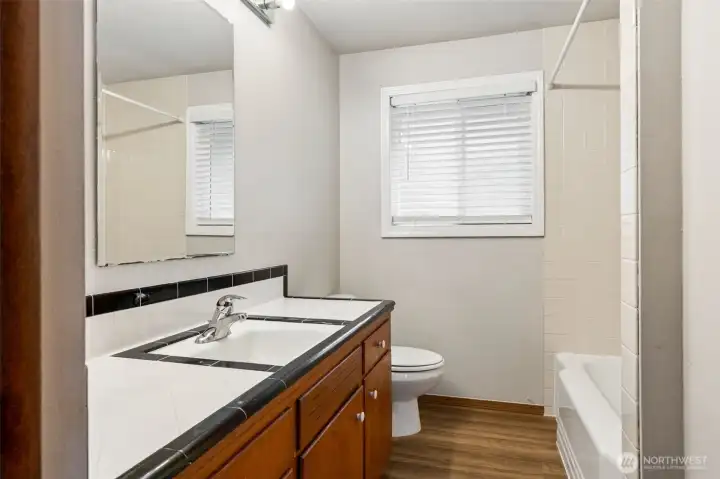 Full bathroom with tile countertop and backsplash.
