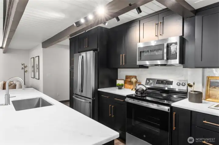 The impeccably designed kitchen is a chef's dream, boasting an abundance of sleek cabinetry, subtle under-cabinet task lighting, and premium matching stainless steel appliances. Expansive white quartz countertops provide endless prep space and wrap into a massive island perfect for casual dining. With fluid transition from the kitchen to the main living area, this light-filled home is an absolute masterpiece for both entertaining and luxurious daily living.