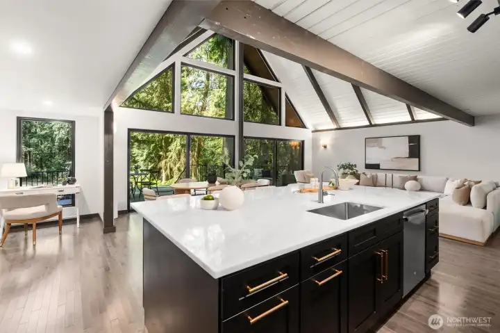 The impeccably designed kitchen is a chef's dream, boasting an abundance of sleek cabinetry, subtle under-cabinet task lighting, and premium matching stainless steel appliances. Expansive white quartz countertops provide endless prep space and wrap into a massive island perfect for casual dining. With fluid transition from the kitchen to the main living area, this light-filled home is an absolute masterpiece for both entertaining and luxurious daily living.