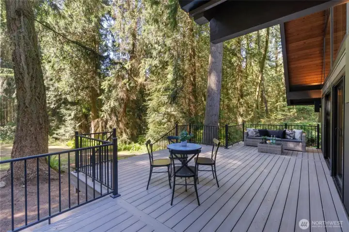 Seamlessly extending from the dramatic 20-foot great room sliders, this massive custom deck redefines open-air luxury. Crafted from premium, ultra-durable composite—the "forever material"—it offers a flawless, splinter-free surface designed to look spectacular for decades with virtually zero maintenance.  ?Step down from the expansive deck into a huge, lush yard wrapped in a peaceful forest backdrop. At the heart of it all sits a dedicated firepit zone, the ultimate setting for crisp evenings, starlit conversations, and roasting s'mores. From lively summer barbecues to quiet morning coffees surrounded by nature, this backyard is built for unforgettable moments.
