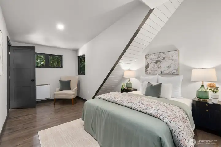 Tucked away on the upper level, this impressive fourth bedroom is a complete self-contained retreat. Dramatic, sharply angled cathedral ceilings lined with clean white planking and anchored by bold dark beams give the room an airy, sophisticated vibe. Large windows bring the tranquil forest views right to the bedside. Perfect for guests, older children, or a second primary setup, this room offers the ultimate privacy with its own dedicated walk-in closet and a gorgeous attached ensuite bathroom featuring a modern vanity and premium finishes.