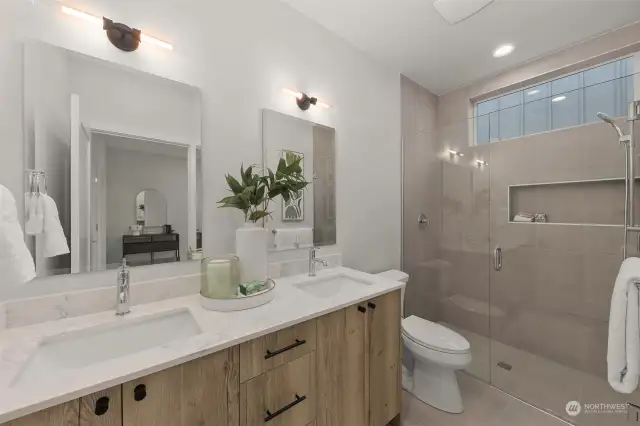 Step into relaxation in this luxurious glass-enclosed rain shower, complemented by sleek tile finishes and stylish double sinks.