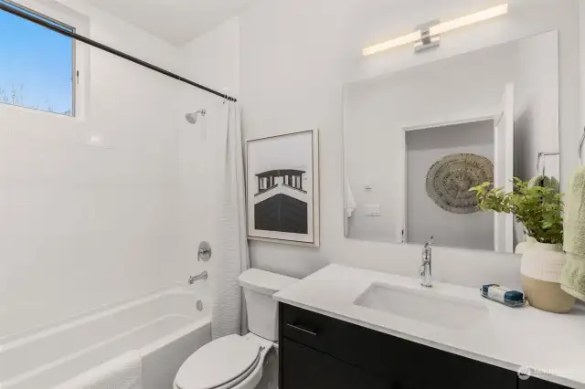Fresh and functional, the second bathroom features a clean design with a full tub, modern fixtures, and charming accents.