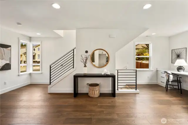 Wide angle shot of the light and bright main living areas, including the built-in desk area and the stairs going both up and down.