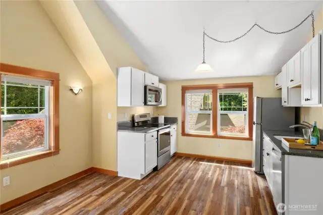This view shows the dining area and full kitchen with stainless steel appliances (including a microwave and dishwasher).