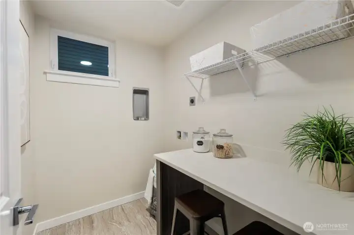 Walk in Laundry room features quartz-topped counters and additional storage area both underneath and above.  Space for a Full size stacking washer and dryer area, and natural light and tiled floors complete this room.