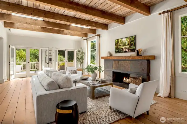 Warm and inviting living room featuring exposed wood beams, built-in shelving, and a statement fireplace.