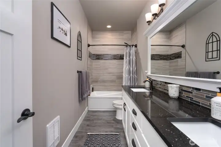 Modern full bath with tile shower, double vanity, and lighting
