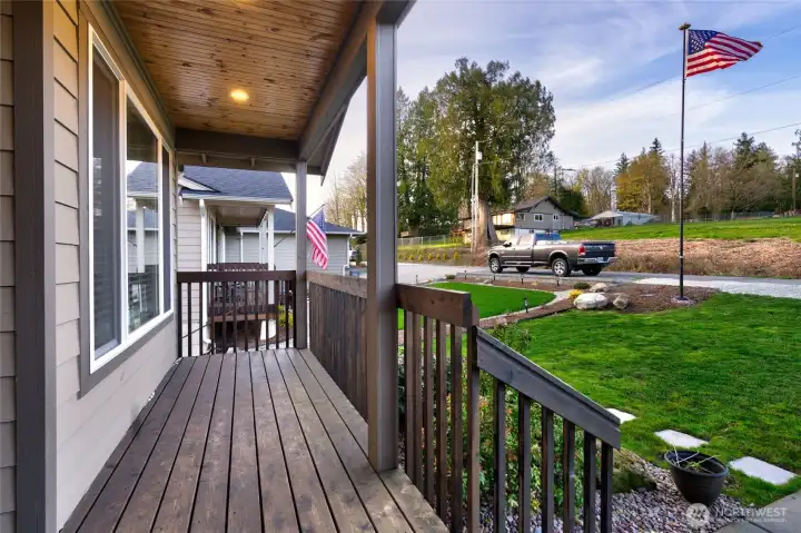 Covered front porch with wood deck and landscaped yard