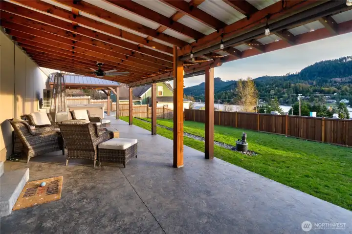 Covered patio with seating, string lights, and backyard views