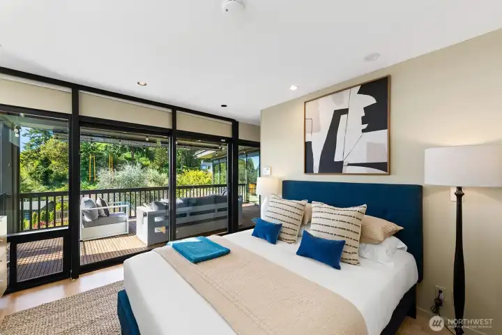 Serene primary suite featuring extensive custom cabinetry and wall-to-wall glass and direct access to a private view deck
