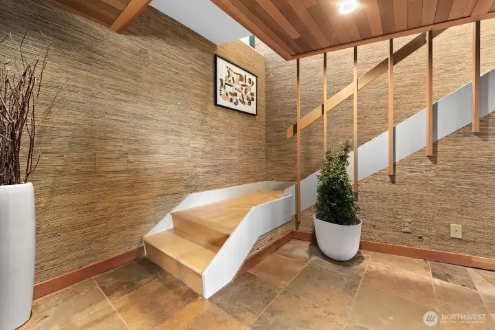 Architectural stairway with warm wood ceilings, custom stair design, and textured walls for a striking first impression