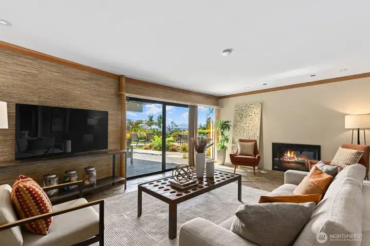 Inviting family room with cozy fireplace and expansive sliding doors opening to the patio—seamless indoor-outdoor living with beautiful garden views