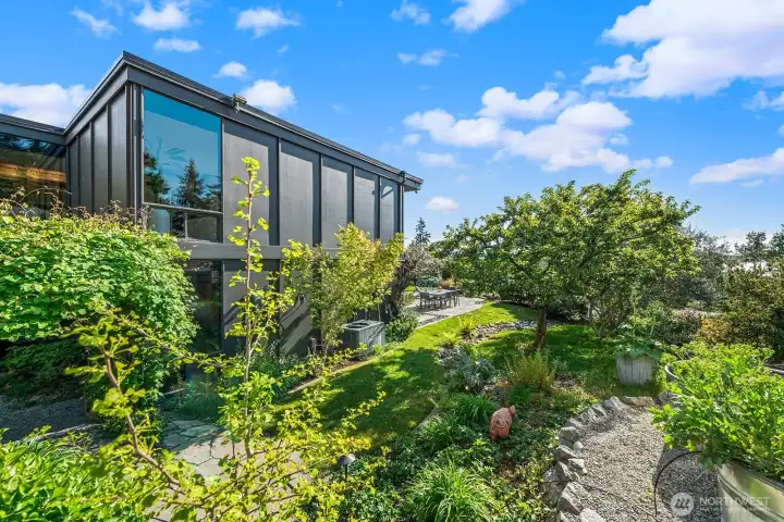 Beautifully landscaped grounds wrap the home with curated plantings, stone pathways, and multiple outdoor spaces for entertaining and everyday living