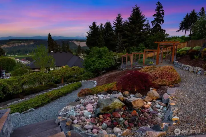A custom waterfall with built-in lighting and softly lit concrete creates a warm, inviting ambiance across the patio.